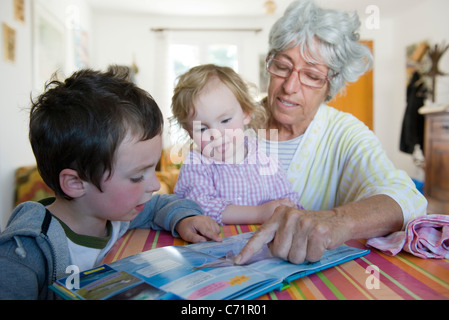 Grandmother reading book with young grandchildren Stock Photo