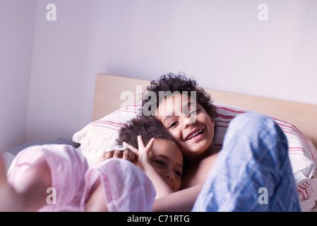 Young brother and sister lying on bed in pajamas Stock Photo