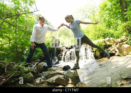 Couple standing on rocks by waterfall Stock Photo