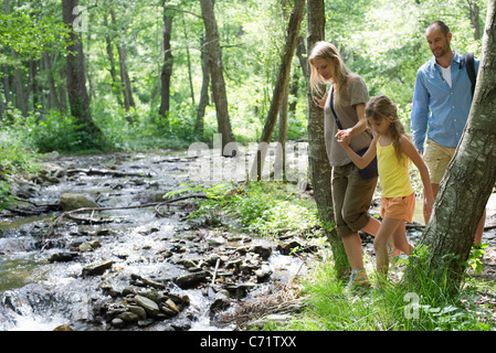 Family hiking along stream in woods Stock Photo