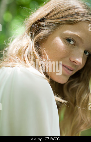 Young woman smiling over shoulder at camera, portrait
