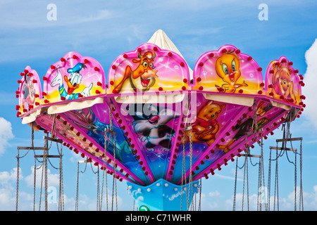 Brightly coloured pink top of a fairground ride or carousel against a blue sky Stock Photo