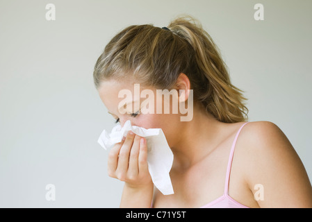Young woman sneezing into tissue Stock Photo