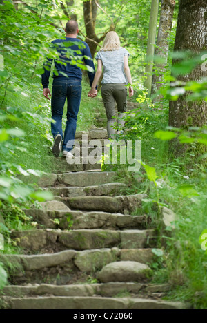 Couple walking up stone steps in woods Stock Photo