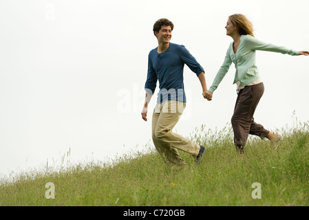 Couple holding hands running on meadow Stock Photo