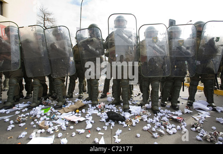 Line of Chilean police in full anti riot gear receiving paper balls from students protesting in Santiago de Chile Stock Photo