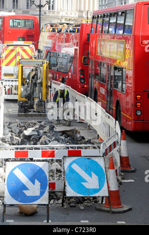 Aerial view workers & mini excavator working on road works in bus lane beside traffic jam of red double decker buses Regent Street West End London UK Stock Photo