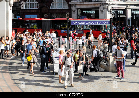 London street scene crowd of people around Oxford Circus & underground tube station at busy retail shopping area & West End road junction England UK Stock Photo