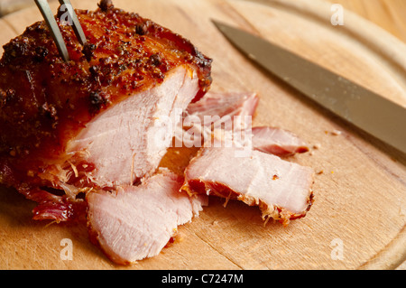 Freshly carved slices of Roast Ham with a honey and mustard / clove glaze - on a wooden board. UK. Stock Photo