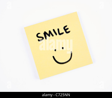 A yellow smiley face is drawn on a sheet of paper and is surrounded by ...