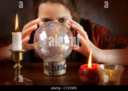 Young fortune teller in a red scarf working with her crystal ball Stock Photo