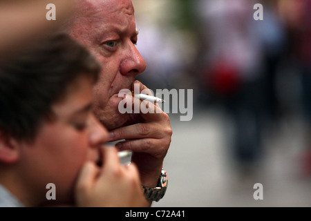 The head of a mature man and a young boy both puffing on a cigarette Stock Photo