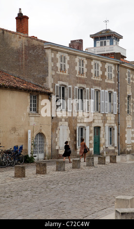 French street scene showing a shuttered house and two women walking along the street Stock Photo