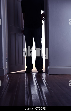 Male figure stepping into a dark room. Stock Photo