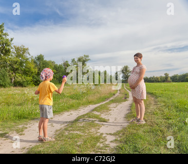 Small boy making soap bubbles with his regnant mother in the green field