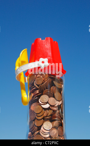 Euro coins in jar with bucket and spade on top. Holiday money concept image Stock Photo