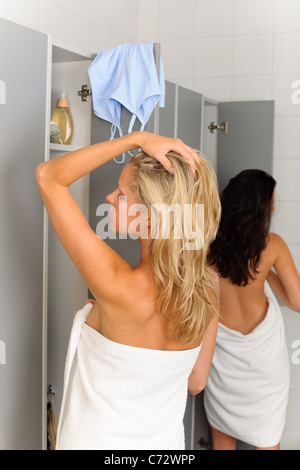 Locker room two relaxed women wrapped in towel going shower Stock Photo