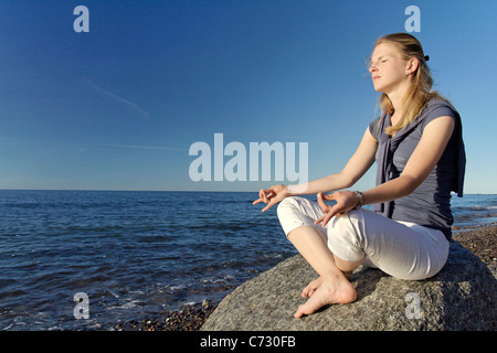 Woman meditating on the beach Stock Photo