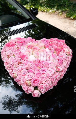 pink roses bouquet mounted on black car hood at wedding ceremony, germany, europe Stock Photo