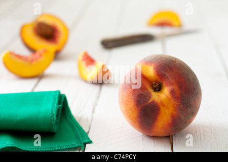Clingstone Peaches on White Wooden Table with Knife and Green Napkin Stock Photo