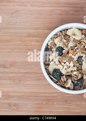 Muesli in a bowl on a bamboo wood board. From above side of frame Stock Photo