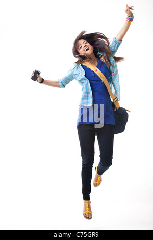 Excited female university student dancing while listening music on white background Stock Photo