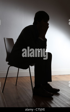 Silhouette of depressed man sitting on walkway of building. Sad man ...