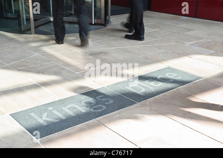 The entrance to Kings Place in London, with revolving doors, the blurred feet of two passing businessmen, and the building logo. Stock Photo