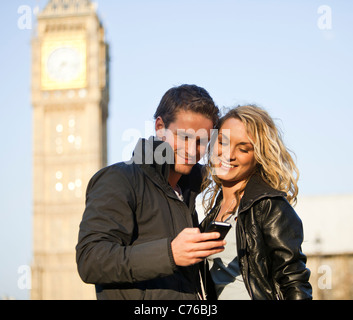 UK, London, Young couple looking at mobile, Big Ben in background Stock Photo