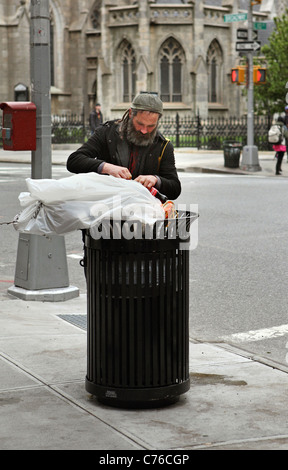 Homeless person rummaging through a trash can, looking for ...