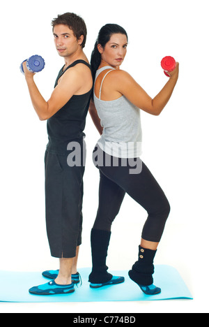 Young couple doing fitness exercises with barbell and standing back to back on blue mat Stock Photo