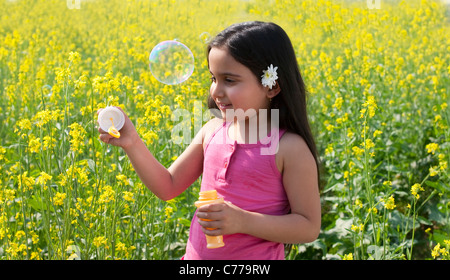 Young girl making bubbles in a field Stock Photo