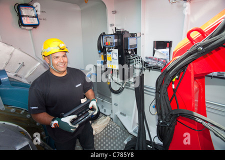 Engineers work in the nacelle of an offshore wind turbine to commission it, Walney offshore wind farm, Cumbria, UK. Stock Photo