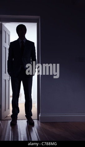 Silhouette of a man standing in front of an open door. Stock Photo