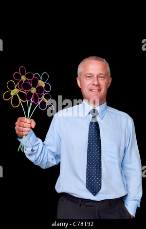 Photo of a mature businessman against a black background holding a bunch of handrawn chalk flowers Stock Photo