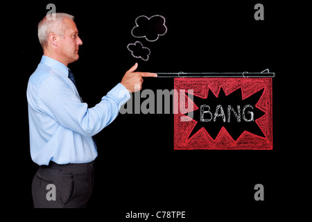Photo of a mature businessman against a black background firing a chalk drawn gun with a BANG flag. Stock Photo