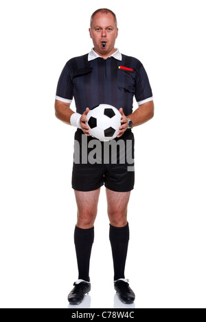 Full length photo of a football or soccer referee holding a ball with a whistle in his mouth, isolated on a white background. Stock Photo