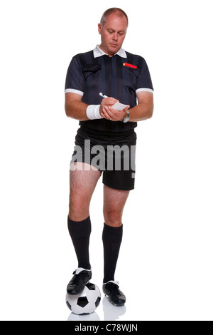 Full length photo of a football or soccer referee with ball writing in his report book, isolated on a white background. Stock Photo