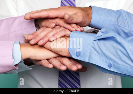 Photo of three business people stacking hands to represent teamwork. Stock Photo