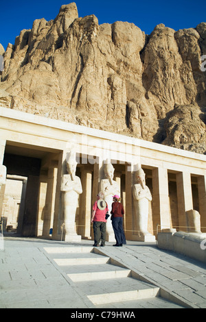 A tourist couple look at the Osiride statues at the Mortuary Temple of Hatshepsut on the West Bank of the Nile at Luxor, Egypt Stock Photo