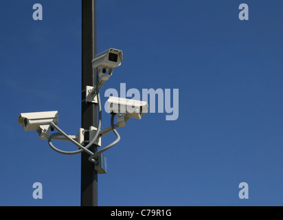 three security video cameras mounted on a pole with a blue sky background and copy space Stock Photo