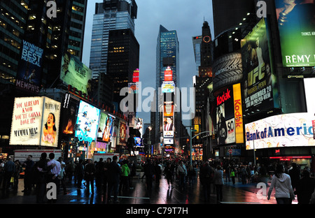 Evening twilight view, towards times Tower, of people, neon signs, rain reflections, skyscrapers, Times Square, New York City Stock Photo