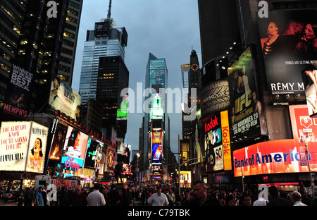 Evening twilight view of people, white shirts, red neon signs, skyscrapers, Times Square, towards Times Tower, New York City Stock Photo