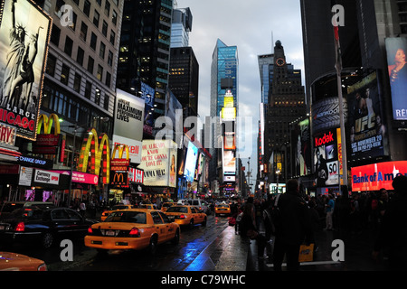 Wet tarmac blue rain reflections twilight view cars yellow taxis people neon skyscrapers theatres, Times Square, New York City Stock Photo