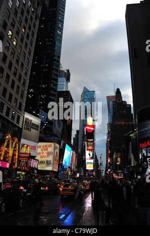 Evening twilight portrait blue rain reflections tarmac traffic people neon skyscrapers, 7th Avenue, Times Square, New York City Stock Photo