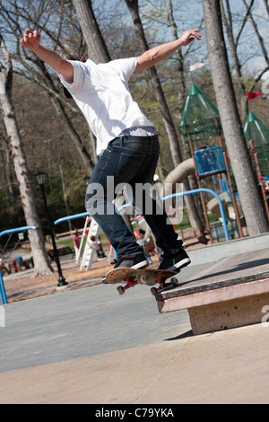 Action shot of a skateboarder performing a jump at a skate park. Stock Photo