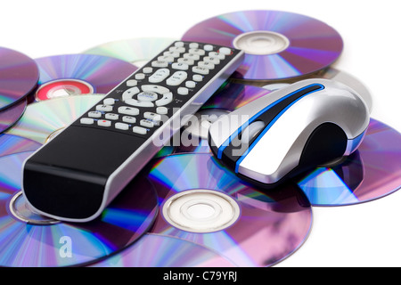 Remote control and computer mouse over a bed of dvd disks isolated over white. Stock Photo