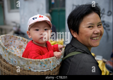 Chinese migrant woman carrying a baby on her back with a bamboo basket in Beijing, China.16-Sep-2011 Stock Photo