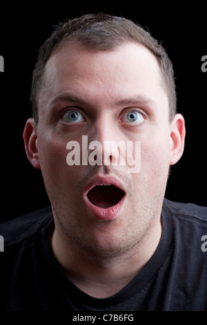 A shocked or surprised middle aged man over a dark background. Stock Photo
