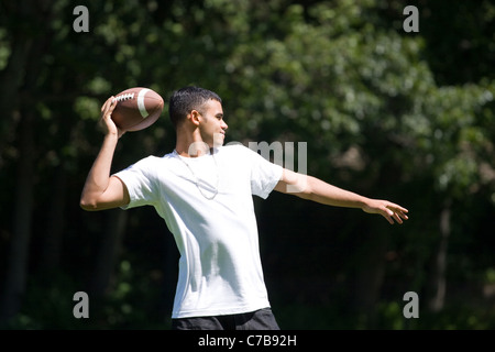 A young man throwing a football outdoors. Stock Photo